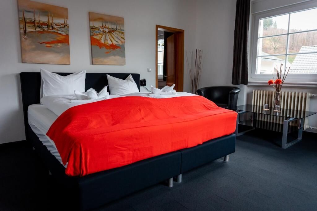 Une chambre à coucher moderne avec un grand lit, une table basse en verre et des œuvres d’art accrochées aux murs.