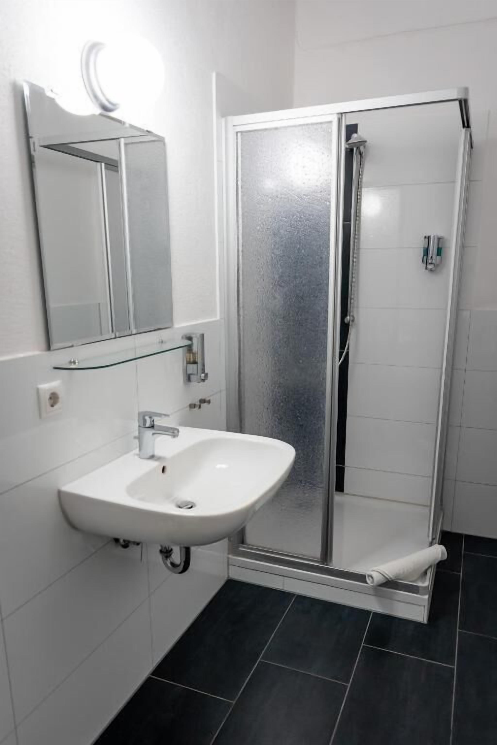 A bathroom with a white sink, a glass shower enclosure, and a mirror.