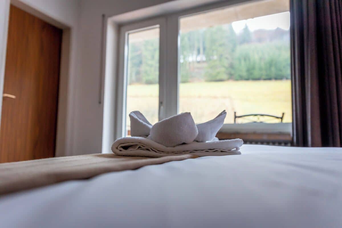 A neatly made bed with a towel and a folded towel on the bed.