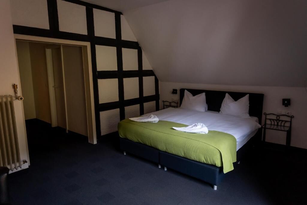 A bedroom with a bed, a radiator, and a door leading to another room.