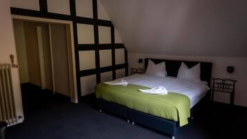 A bedroom with a bed, a radiator, and a door leading to another room.