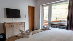 Ein Hotelzimmer mit Bett, Fernseher, Holzschrank und Fenster mit Blick auf ein Feld.