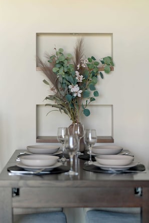 Mesa posta com pratos, copos e um vaso com flores.