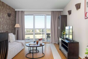 Ein modernes Wohnzimmer mit einer Couch, einem Couchtisch, einem Fernseher und einem Balkon mit Blick.