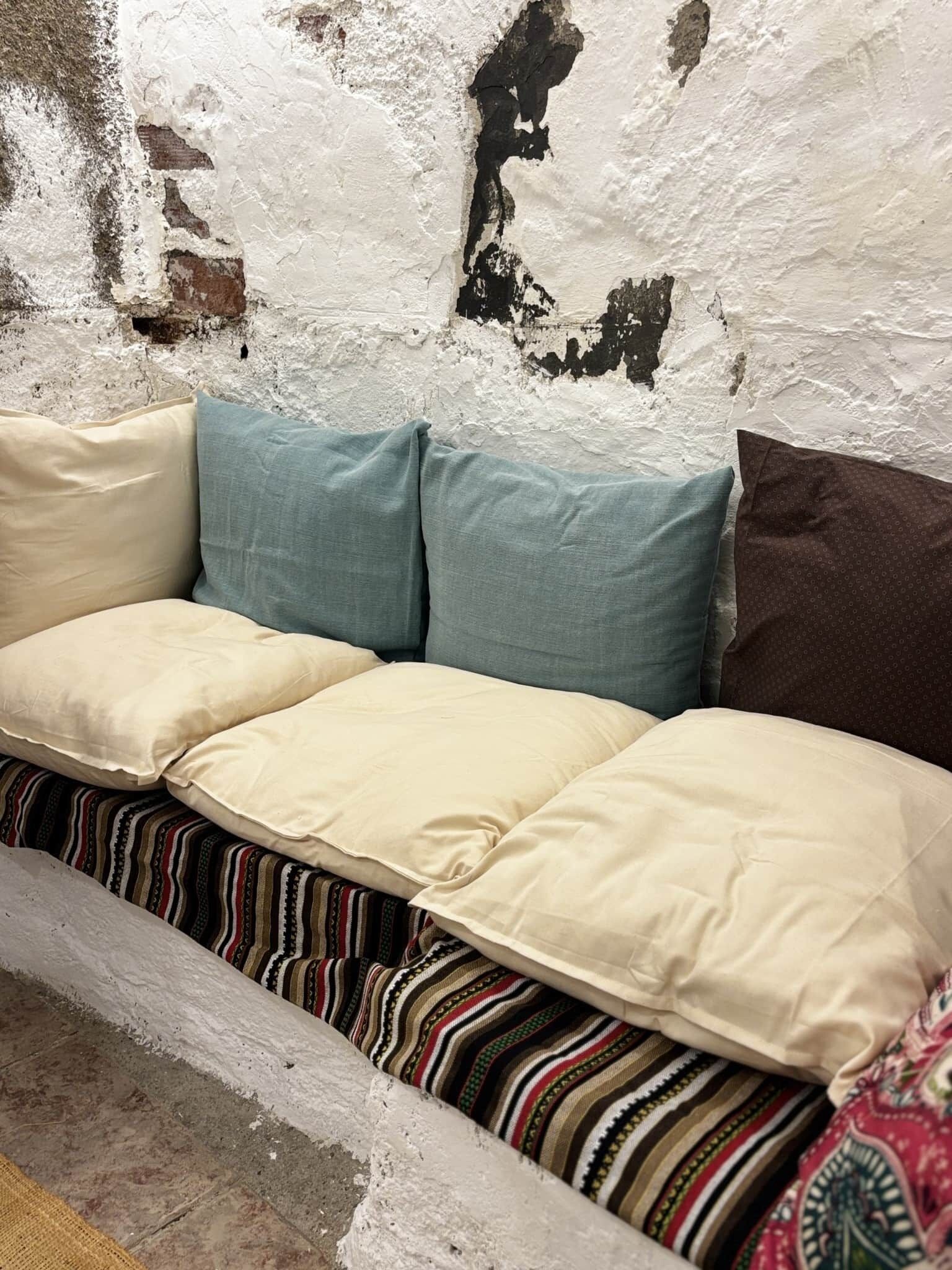 A sofa with multiple cushions against a textured wall.
