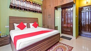A hotel room with a bed, wooden wardrobe, and a door.