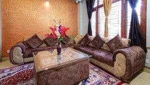 A living room with a sofa set, a glass coffee table, and a patterned rug.