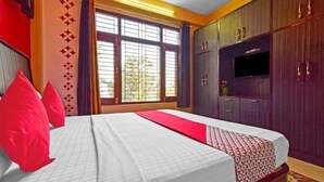 A hotel room with a bed, a television, and a window with curtains.