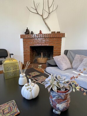 A living room with a brick fireplace, a sofa, decorative vases, and a table with various items.