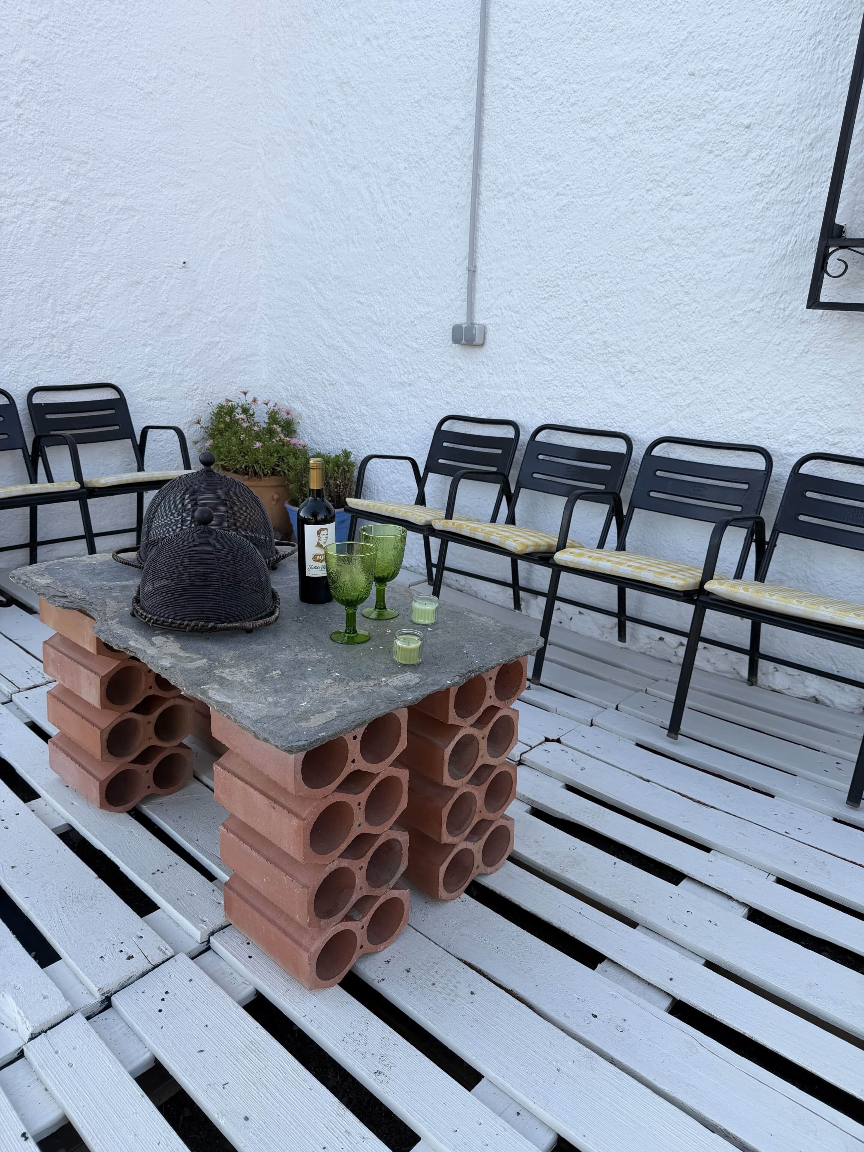 Une table dotée d’un socle original en briques et d’un plateau en métal, entourée de chaises noires.