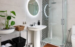 A modern bathroom with a glass shower enclosure, a round mirror, a white sink, and a potted plant. - La Casilla - El Mirador de Gérgal - Rural Living (Gérgal)