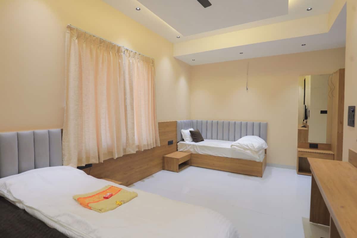Quarto de hotel moderno com duas camas, um pequeno banco de madeira, uma mesa de cabeceira e um espelho.