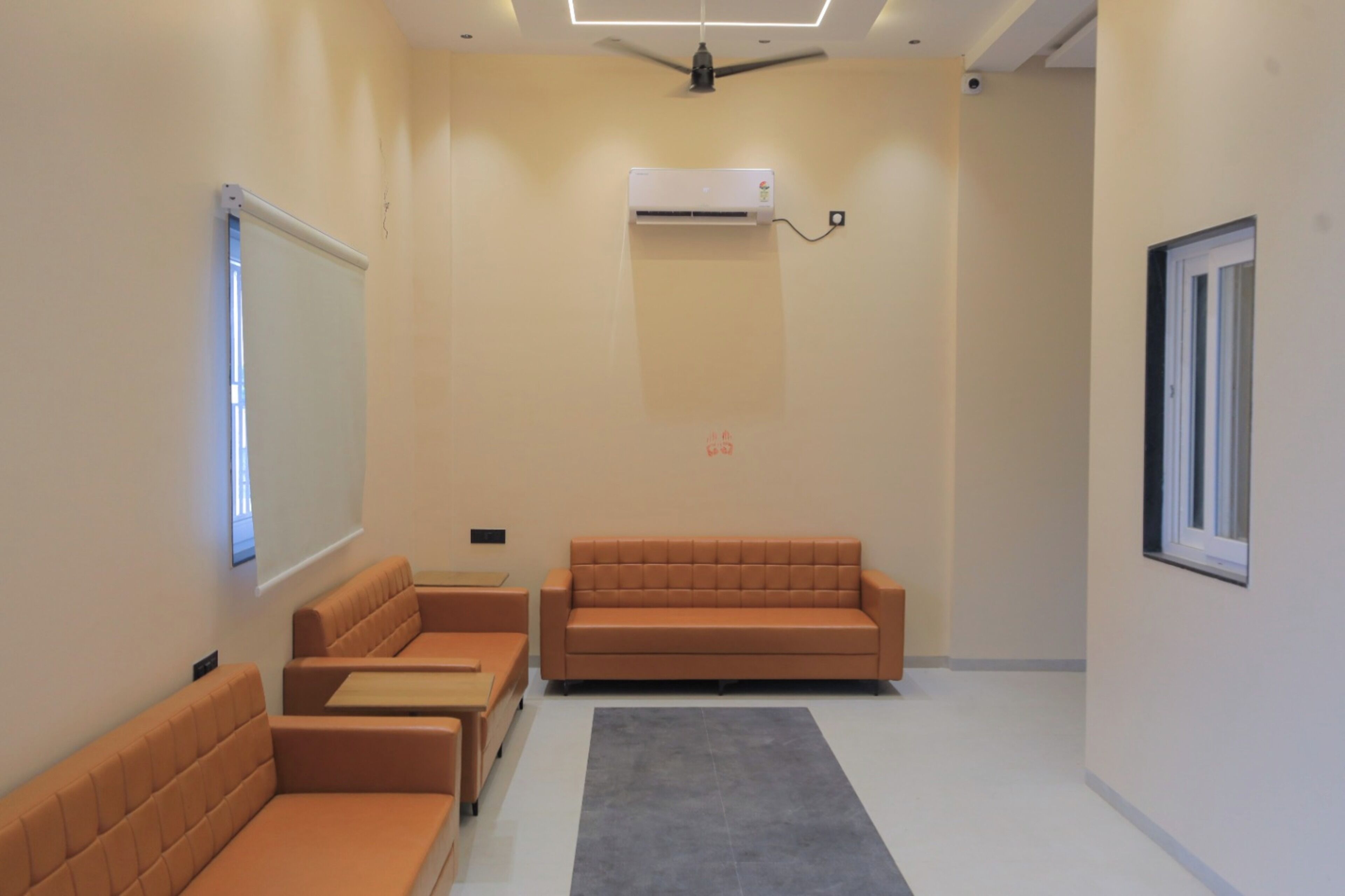 A modern room with a sofa, a small table, a projector screen, and an air conditioning unit.