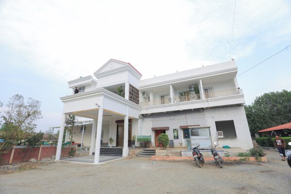 A two-story building with a covered entrance, a balcony on the upper floor, and a motorcycle parked in front.