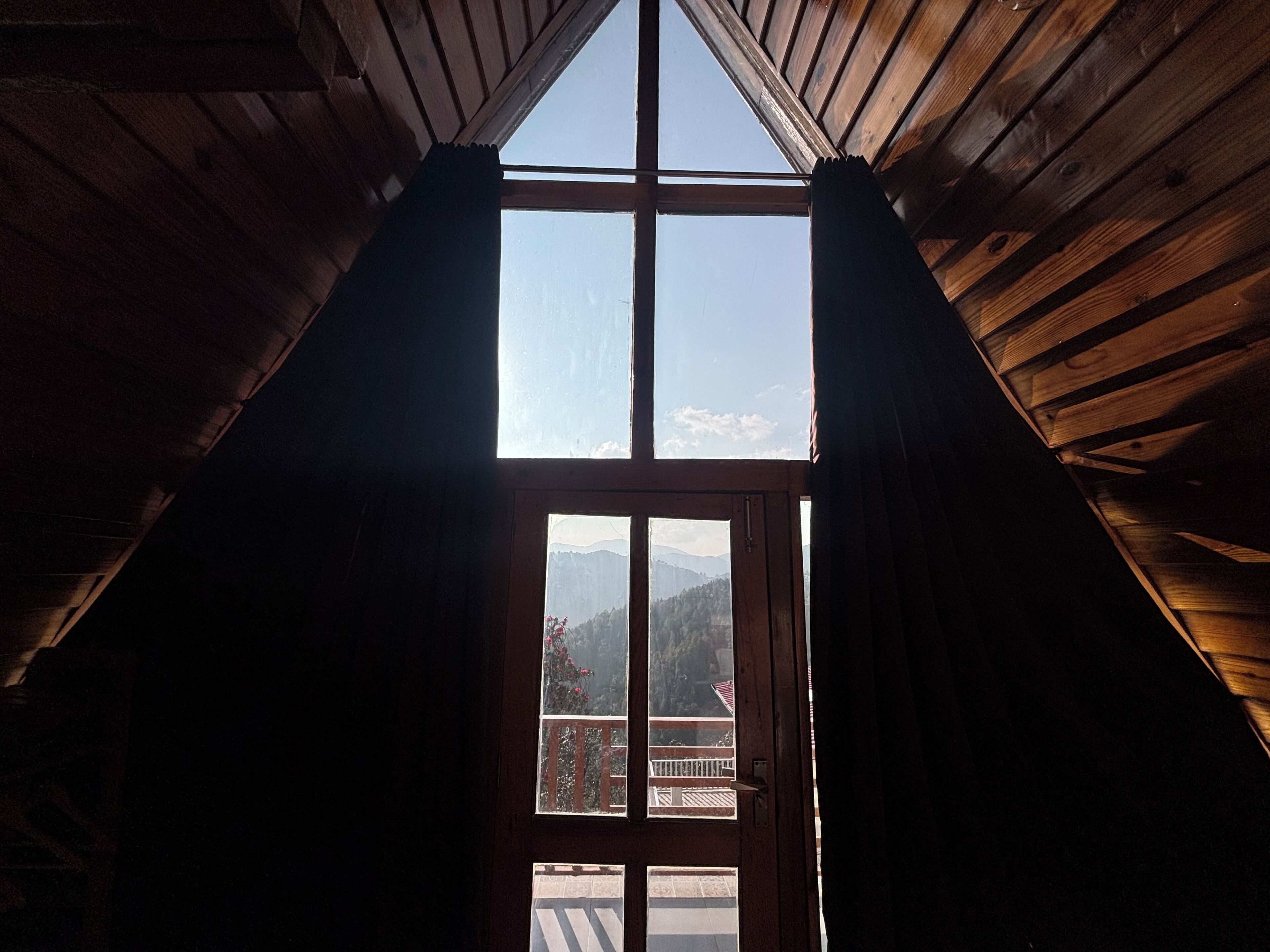 An attic room with a skylight, wooden beams, and a view of mountains.