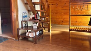 A wooden interior with a wooden staircase, a table with toiletries, and a sign for a QR code menu. - The Woodshed (Mukteshwar)