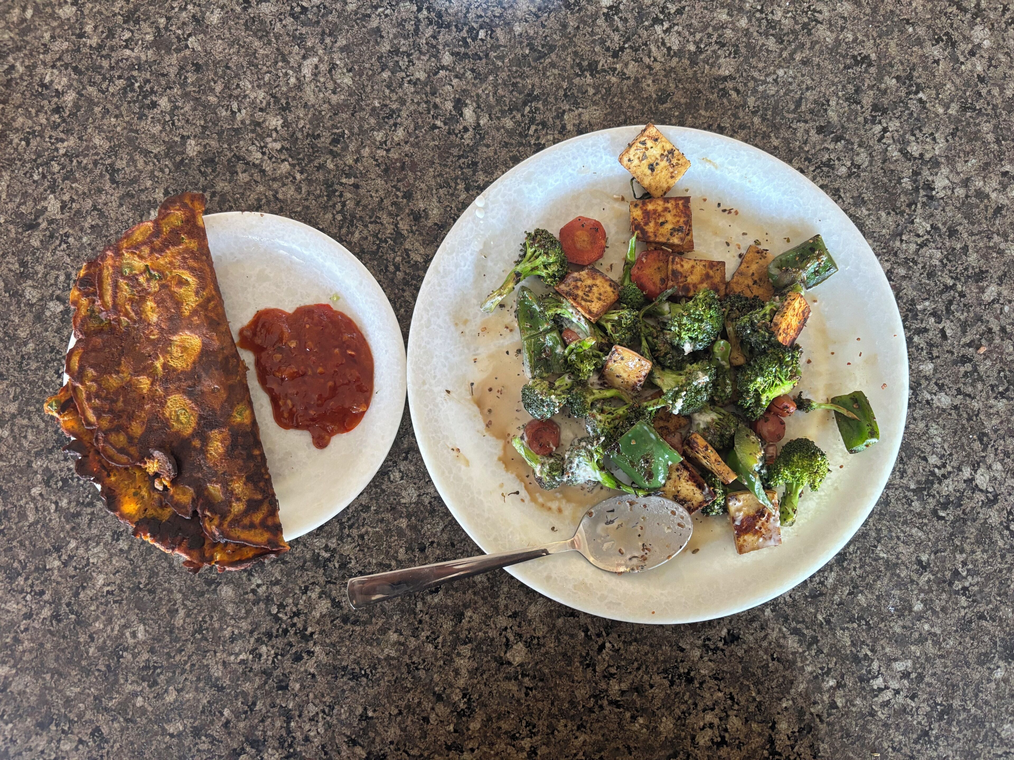 Deux assiettes de nourriture : l’une contient un plat frit et une sauce rouge, et l’autre, une variété de légumes et du tofu.