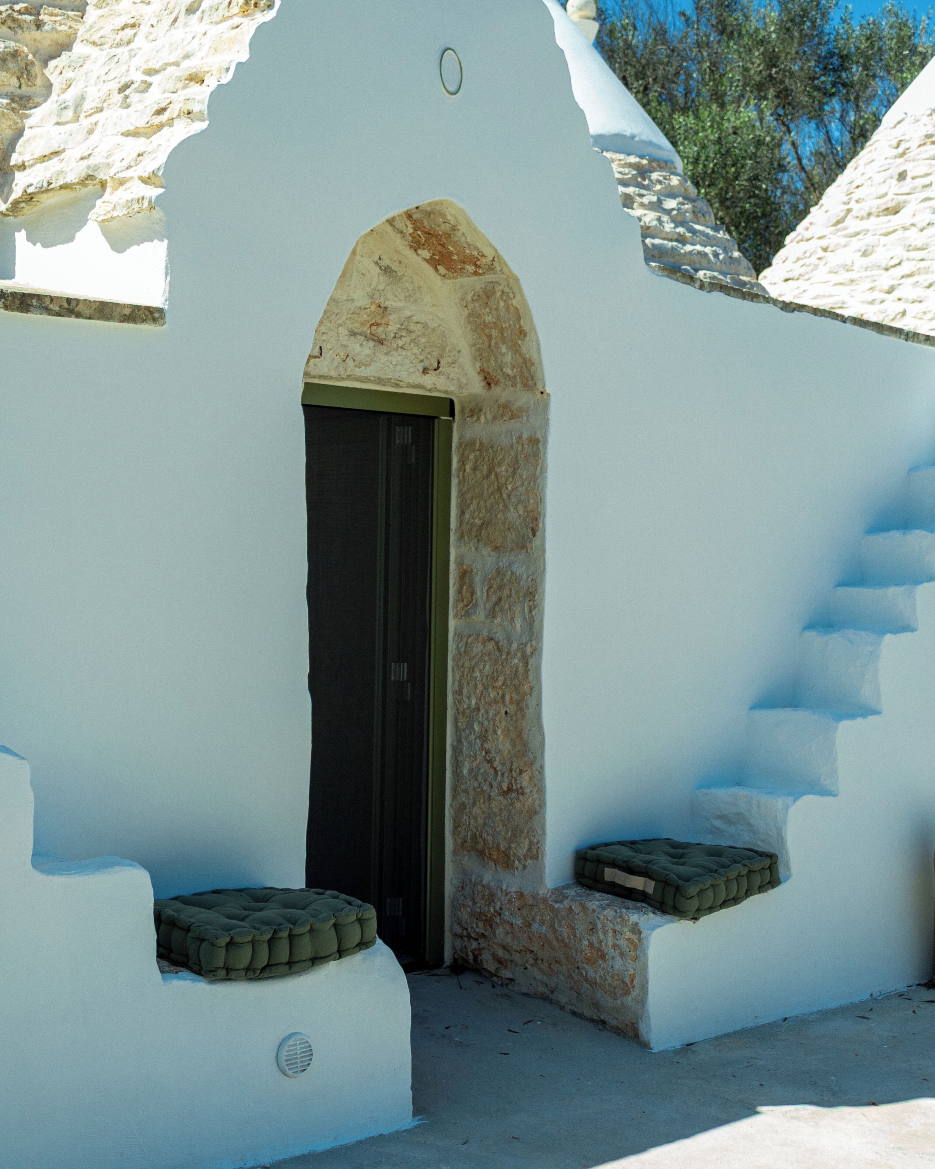 A white building with a black door, stone steps, and a small window.