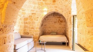 Ein Zimmer mit steinernen Wänden, einem Bett, einer Couch und einem kleinen Tisch.