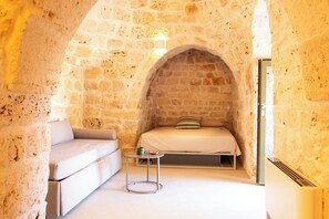 Ein Zimmer mit steinernen Wänden, einem Bett, einer Couch und einem kleinen Tisch.