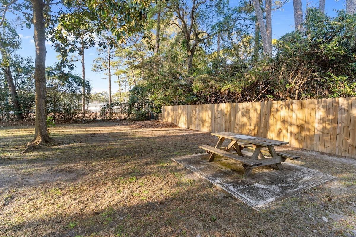 Une table de pique-nique dans un jardin, avec une clôture en bois et des arbres.