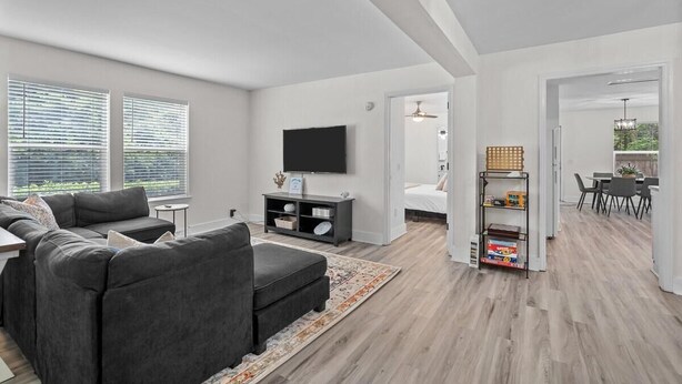 Una sala de estar moderna con un sofá modular, un televisor de pantalla plana, una estantería y una zona de comedor.