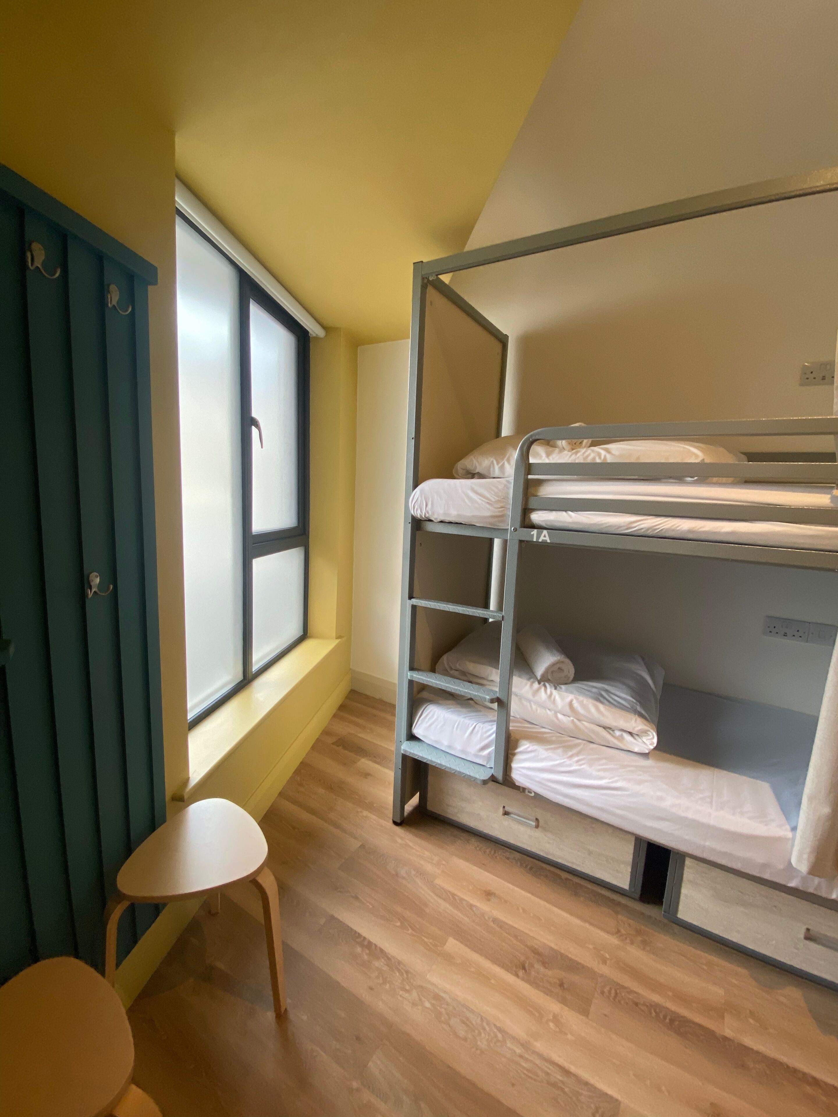 A bunk bed room with a window, a small table, and a door.