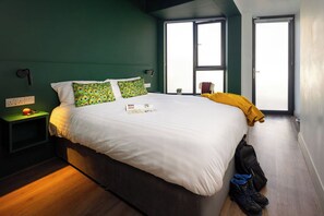 A bedroom with a large bed, a nightstand, a window, and a door. - Heyday Hostel (Ballina)