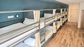 Una habitación con literas, suelo de madera y una puerta.