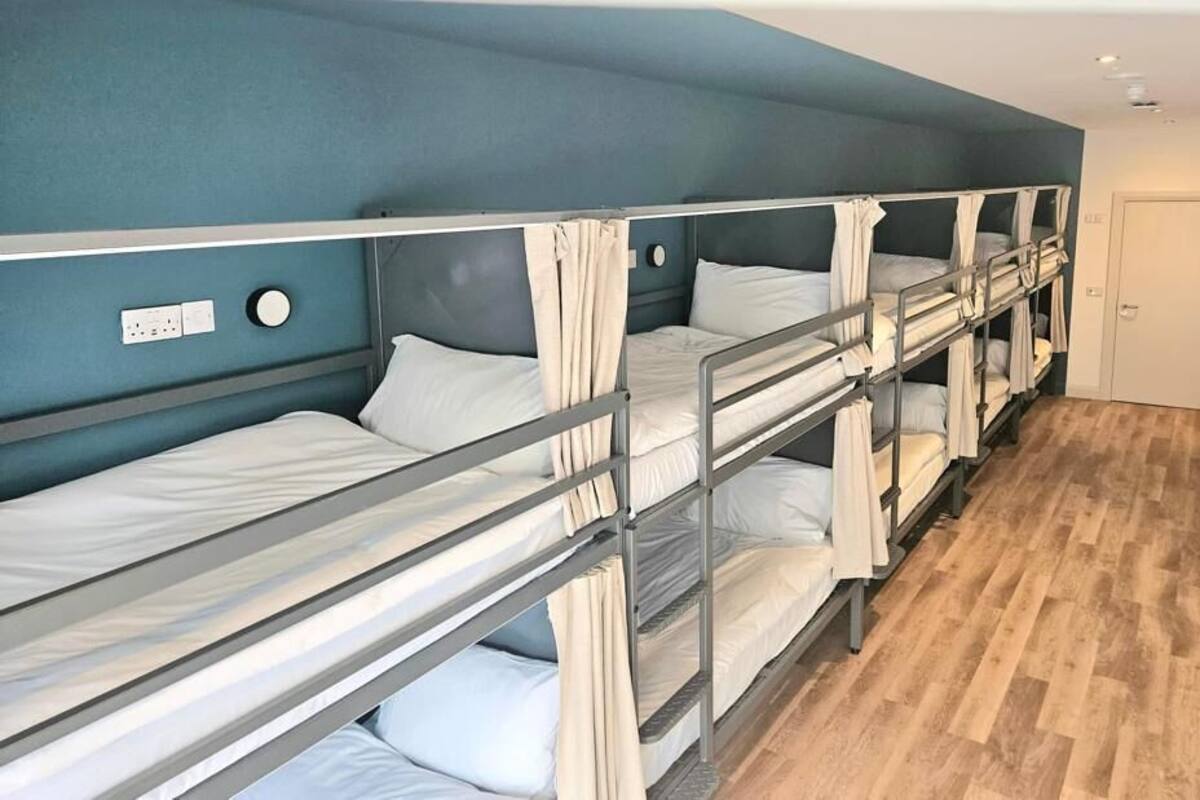 A room with bunk beds, a wooden floor, and a door.