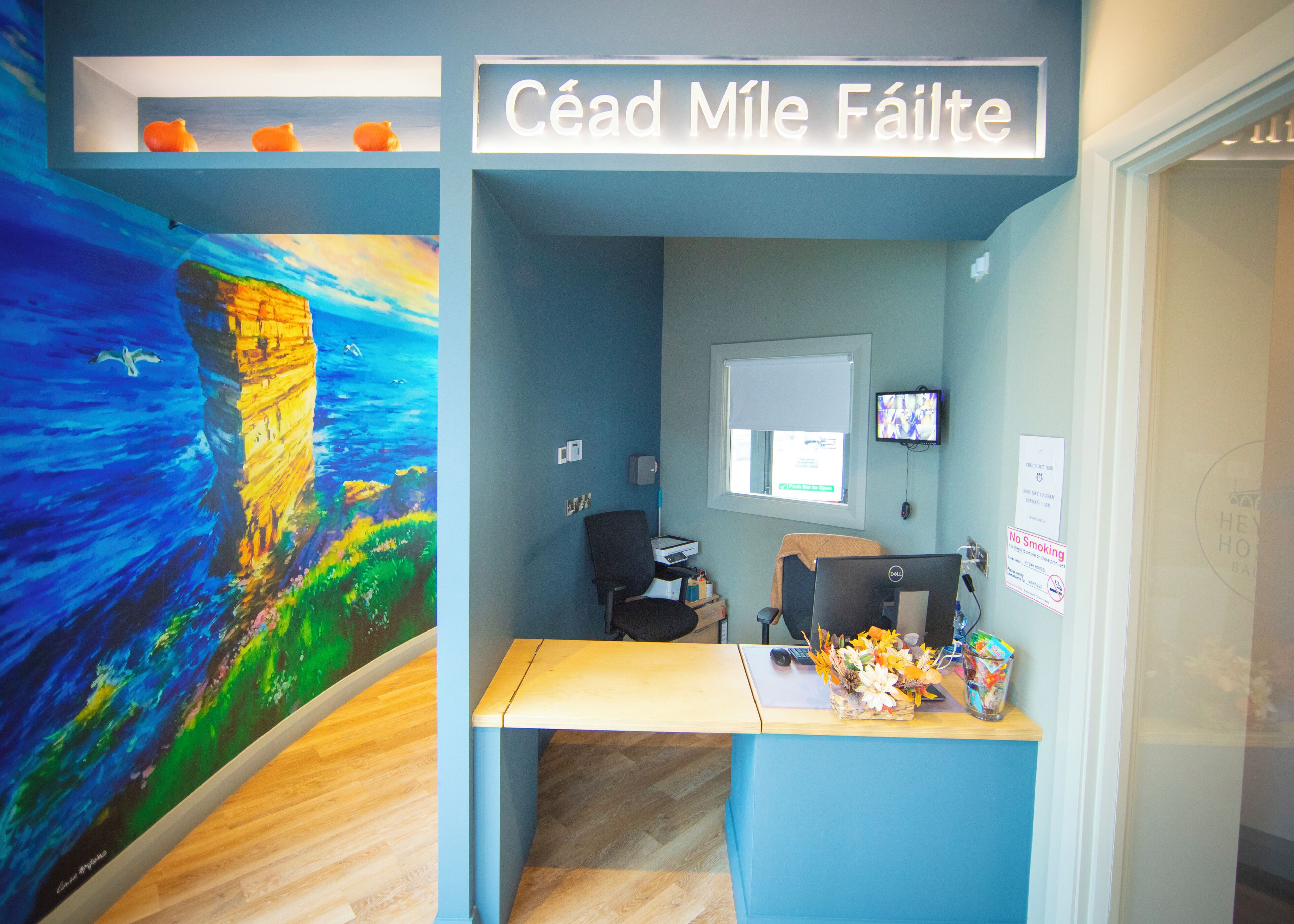A reception desk with a computer, a monitor, and a sign that reads 'Céad MILE Fáilte'.