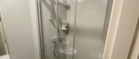 Une salle de bain moderne avec une douche à parois de verre, un lavabo blanc et un tapis en bois.