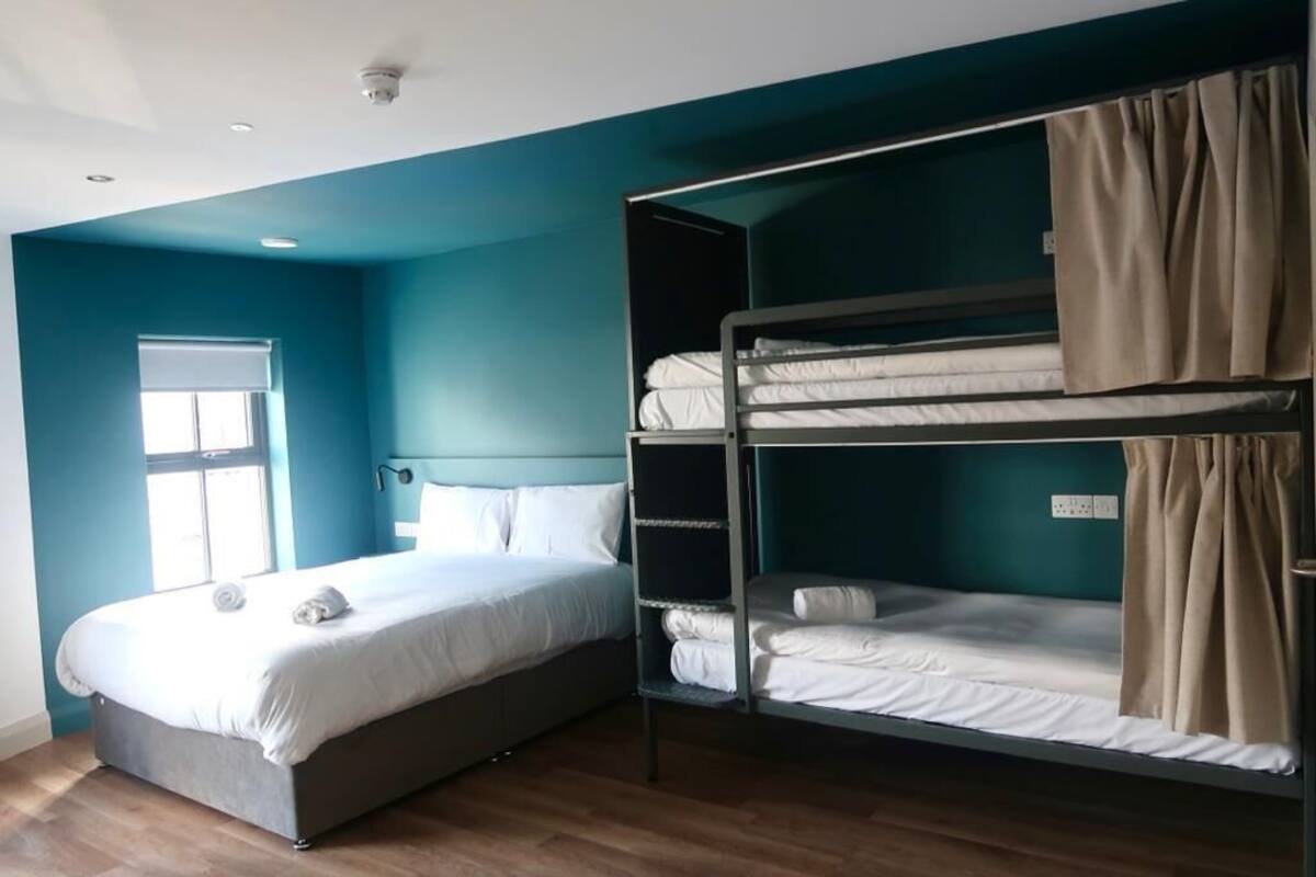 A room with a single bed, a bunk bed, a window, and a ceiling light.