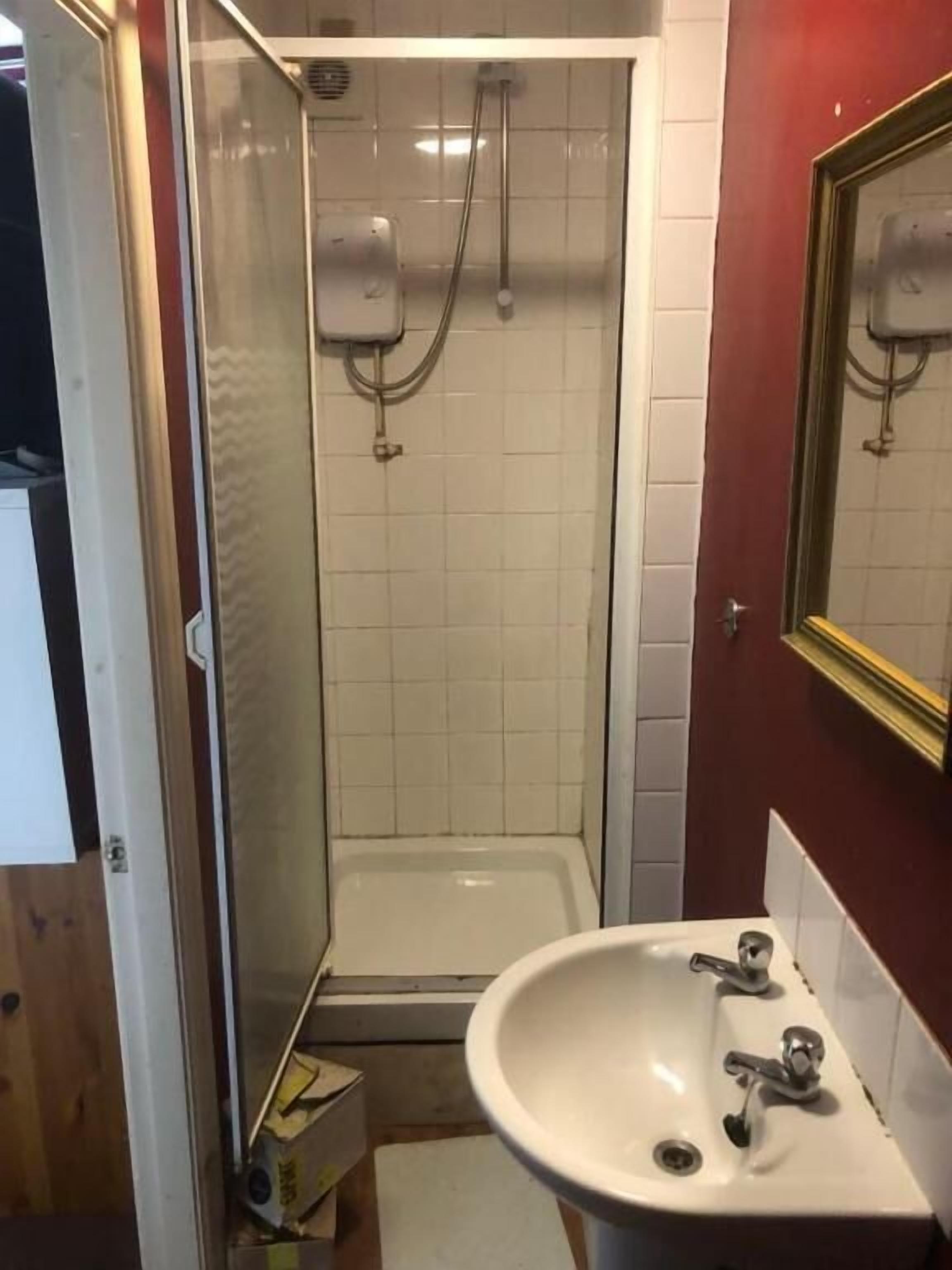 Une salle de bain avec une douche, un lavabo et un miroir.