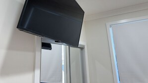 A flat-screen TV mounted on a wall in a room with a door and a window.