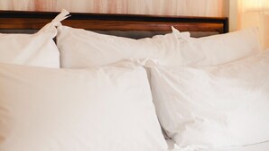 Een net opgemaakt bed met witte lakens en een houten hoofdbord.