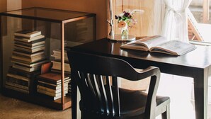 Een werkhoek met een bureau, stoel, boeken, een lamp en een raam met gordijnen.