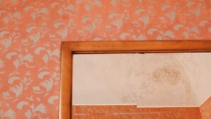 A wall with a floral pattern and a partially visible door frame. - Red Room (Praiano)