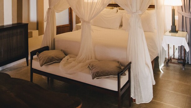 A four-poster bed with a canopy, a bedside table with a lamp, and a television on the wall. - La Grigia (Praiano)