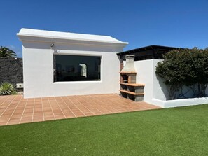 A modern house with a white exterior, a large window, and a brick patio. - Villa oceano charming comfortable house with pool and jacuzzi sea view (Playa Blanca)