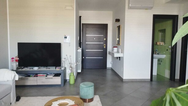 A modern living room with a flat-screen TV, a sofa, a coffee table, and a small rug. - RESIDENCE VIA LECCE (Merine)