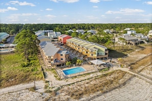 A coastal hotel with multiple buildings, a swimming pool, and a beach area. - Gulf-front condo with access to gulf beaches and two community pools. (Dauphin Island)
