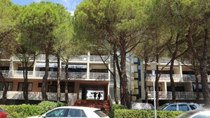 A multi-story building with balconies, surrounded by trees. - Bright Studio With Lovely Balcony (Lignano Sabbiadoro)