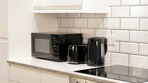 Et køkken med mikrobølgeovn, kaffemaskine og ovn.