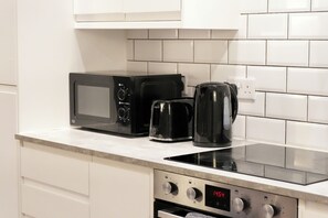 A kitchen with a microwave, coffee maker, and oven. - Spacious 4BR Apartment • 7 Beds • Near Station (Newport)
