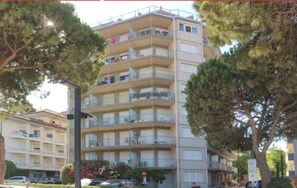 A multi-story building with balconies, a stop sign, and trees. - Ideally Located Beachfront Apartment (Lignano Sabbiadoro)