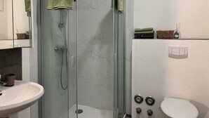Ein modernes Badezimmer mit einer Duschkabine, einem Waschbecken und einer Toilette.