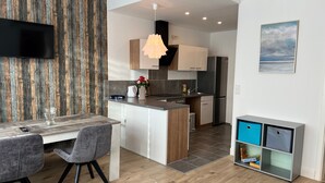 Eine moderne Küche mit Einbauofen, Kühlschrank und Essbereich mit Tisch und Stühlen.