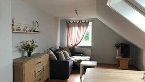 Ein gemütliches Loft-Zimmer mit Schlafgalerie, einem Holzschrank, einem kleinen Tisch und einem Fernseher.
