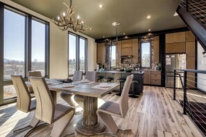 A modern kitchen with a central island, large windows, and a dining area with a table and chairs. - Summit Brownstone Retreat with Elevator & Mount LeConte Views (Sevierville)